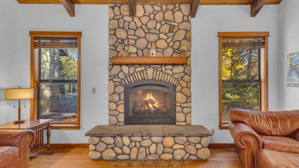 Living room with river-rock fireplace and vaulted wood-beam ceiling